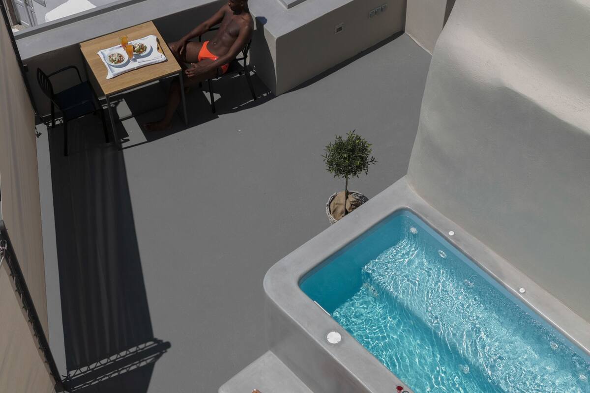 A rooftop pool area with a hot tub and a dining table.