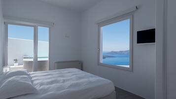 A bedroom with a bed, a TV, and a view of the sea.