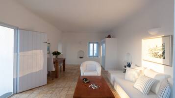 A modern living room with a white sofa, a wooden coffee table, and a dining area with a white chair and table.