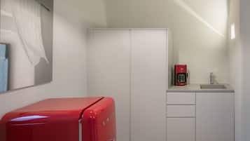 Une cuisine de taille réduite avec un appareil électroménager rouge, un meuble blanc et un évier.