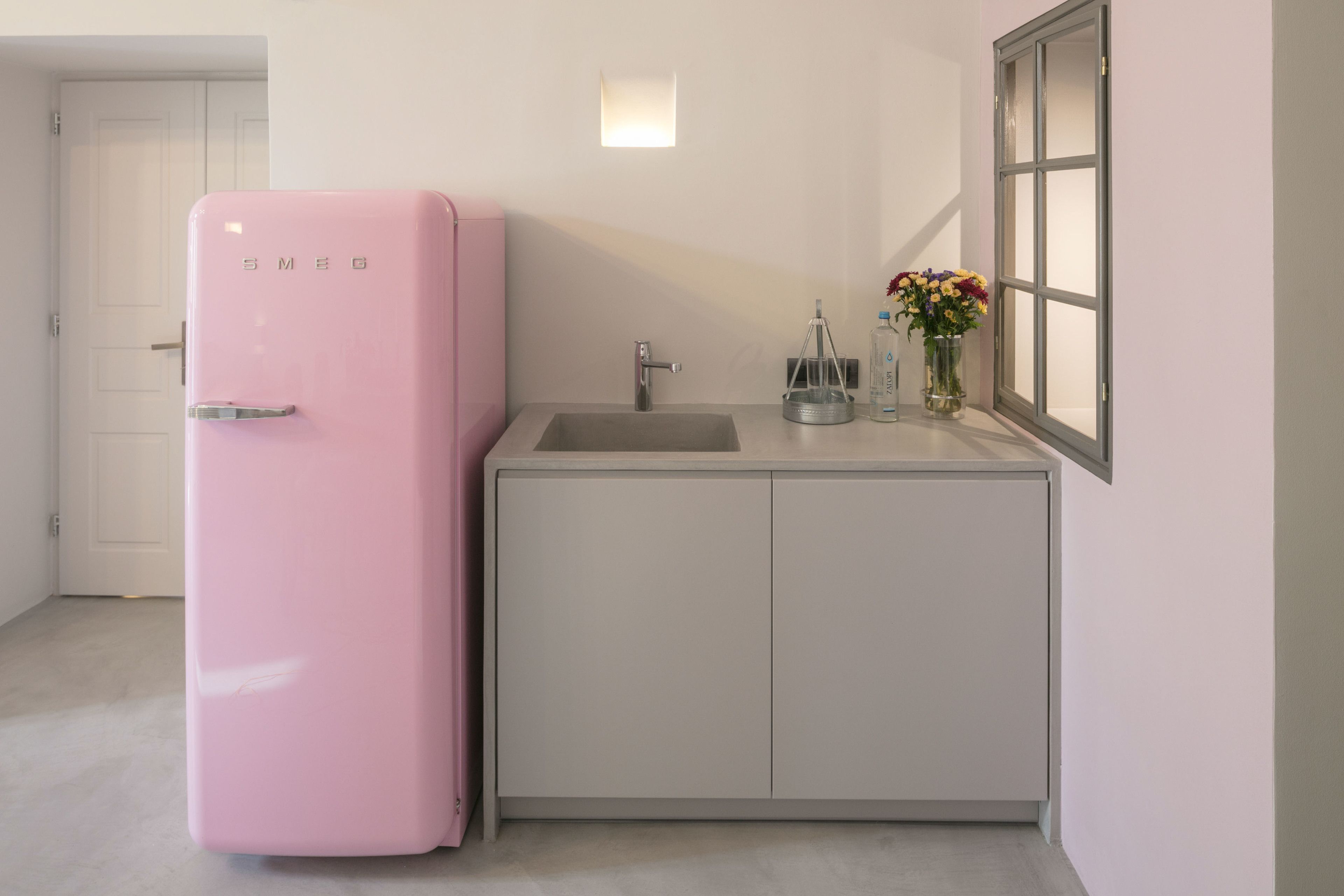 Una cocina compacta con un refrigerador rosa, un lavamanos y una ventana con vistas.