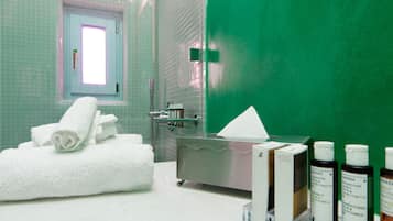 A bathroom with a green wall, a white towel, a sink, and toiletries.