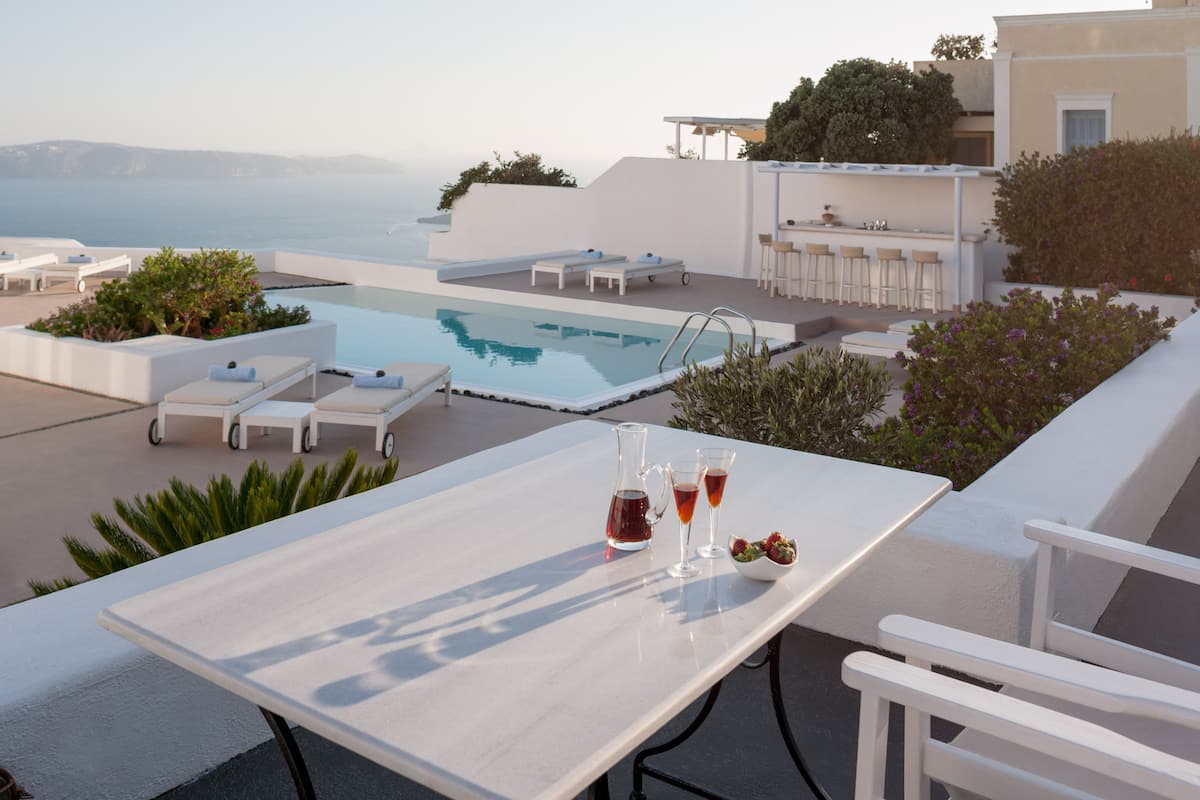 A rooftop pool area with lounge chairs, a table with drinks, and a bar.