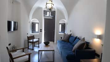 Ein modernes Wohnzimmer mit einem blauen Sofa, Holzstühlen, einem Couchtisch und einem an der Wand befestigten Fernseher.