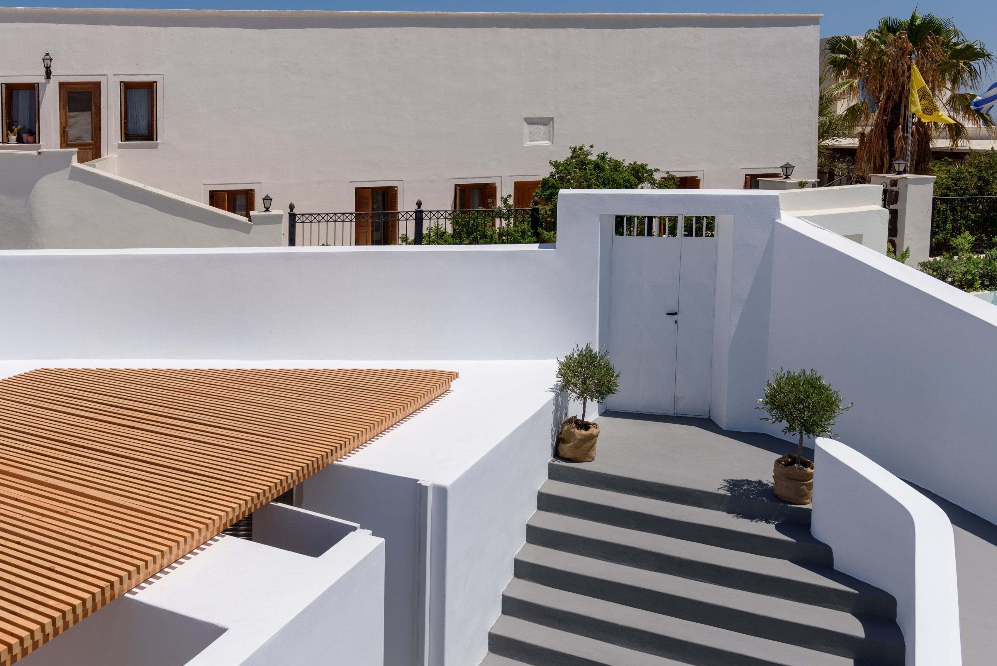 Un edificio blanco con un porche de madera y una escalera que lleva a una puerta.