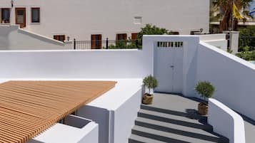 A white building with a wooden deck and a staircase leading to a door.