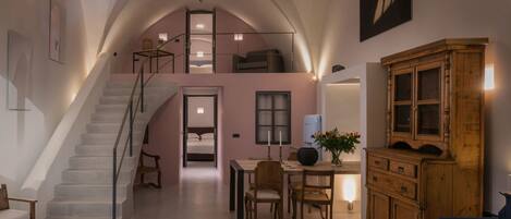 A spacious loft with a staircase leading to a loft bedroom, a dining area with a table and chairs, and a large wooden cabinet.