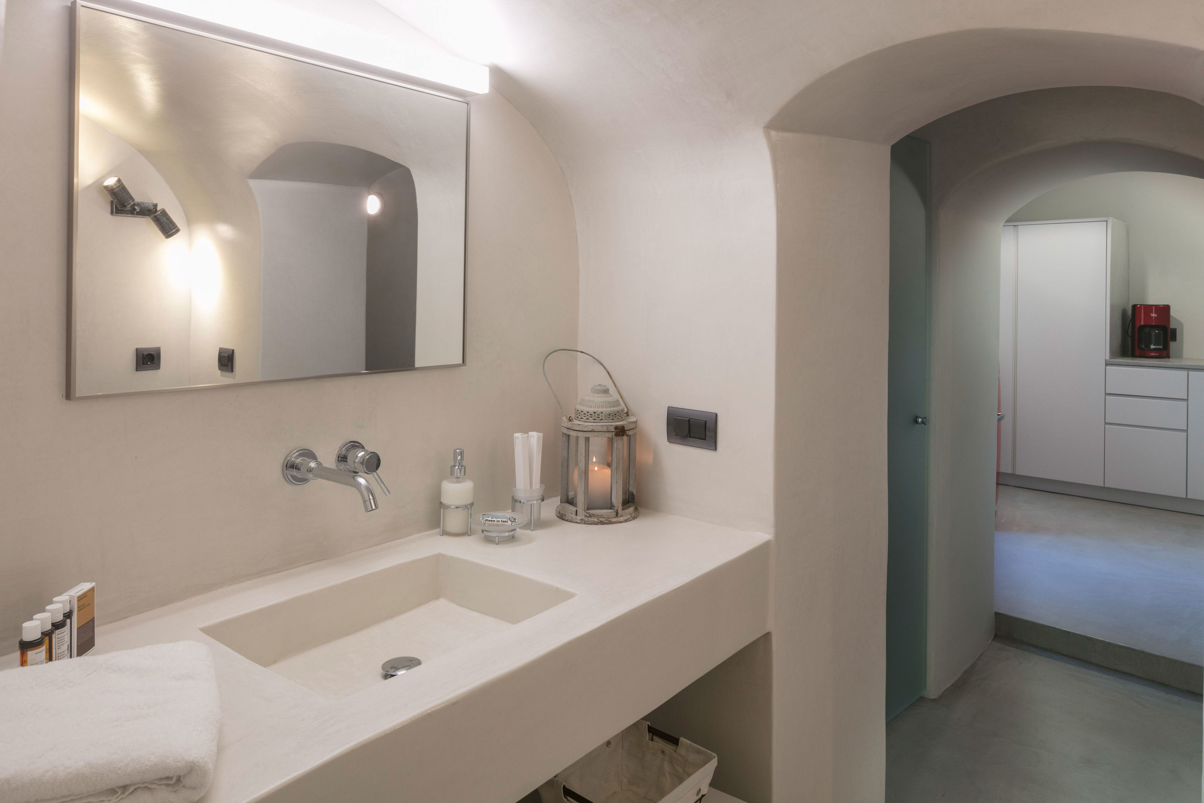 A bathroom with a large mirror, a sink, and a cabinet. There is a towel on the counter and a lantern on the wall.