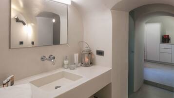 A bathroom with a large mirror, a sink, and a cabinet. There is a towel on the counter and a lantern on the wall.
