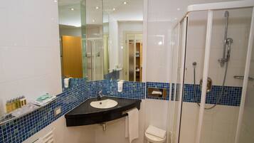 Une salle de bain moderne avec une douche à parois de verre, un lavabo noir et un miroir.