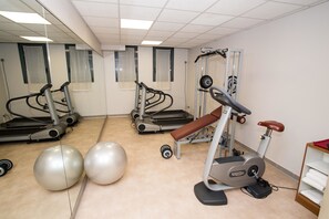 A gym with treadmills, an elliptical, and two large exercise balls. - Best Western Palace Inn Hotel (Ferrara)