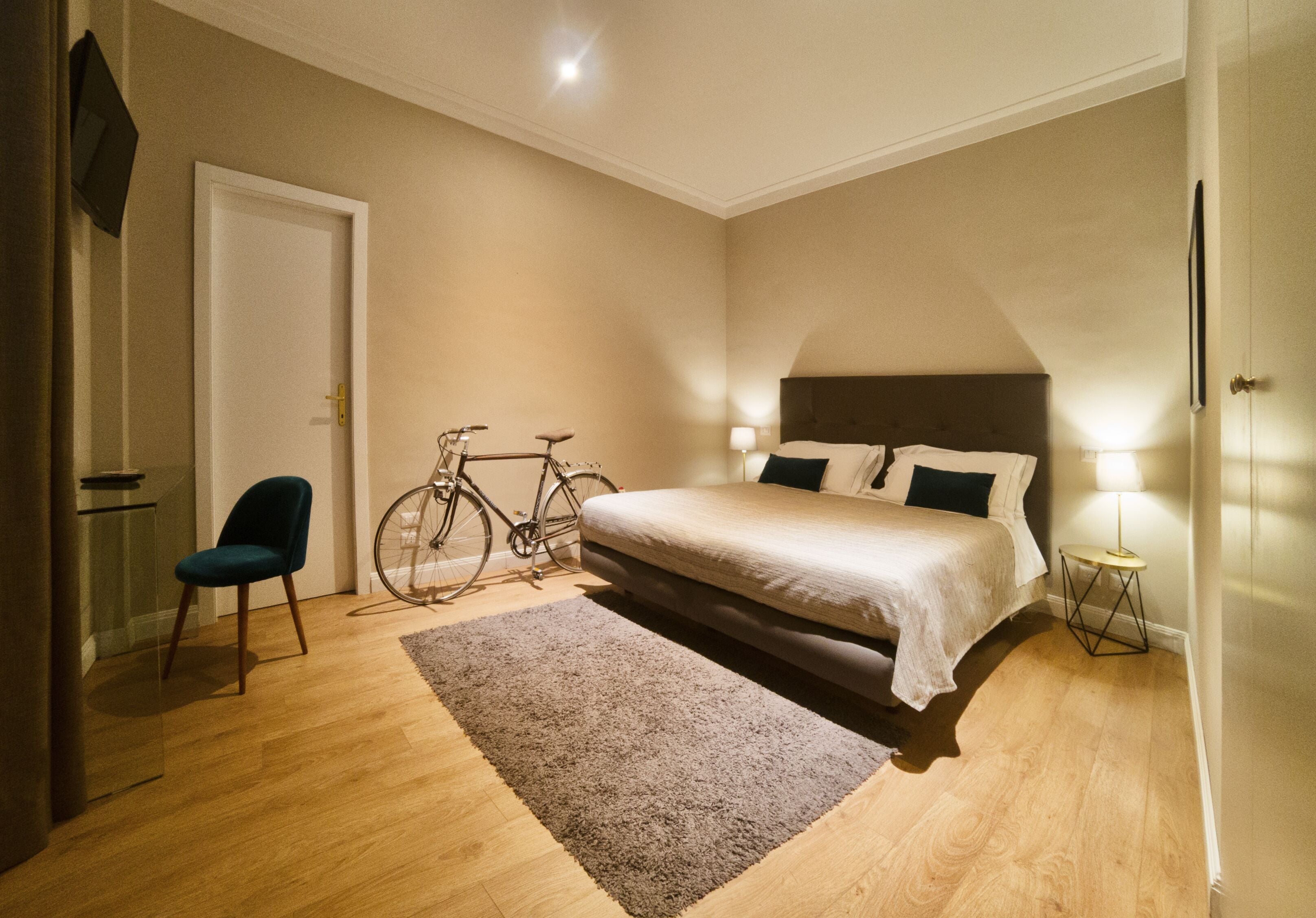 Ein Schlafzimmer mit einem Bett, einem Fahrrad, einem Sessel und einer Lampe.