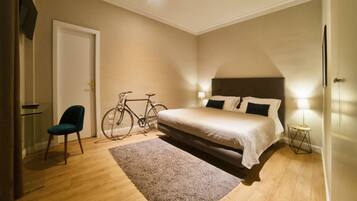 Ein Schlafzimmer mit einem Bett, einem Fahrrad, einem Sessel und einer Lampe.