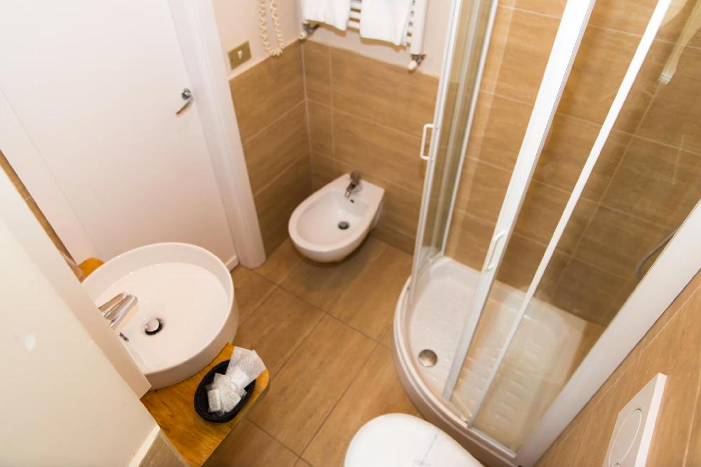 Un baño con lavamanos, bidé y ducha con mampara de vidrio.