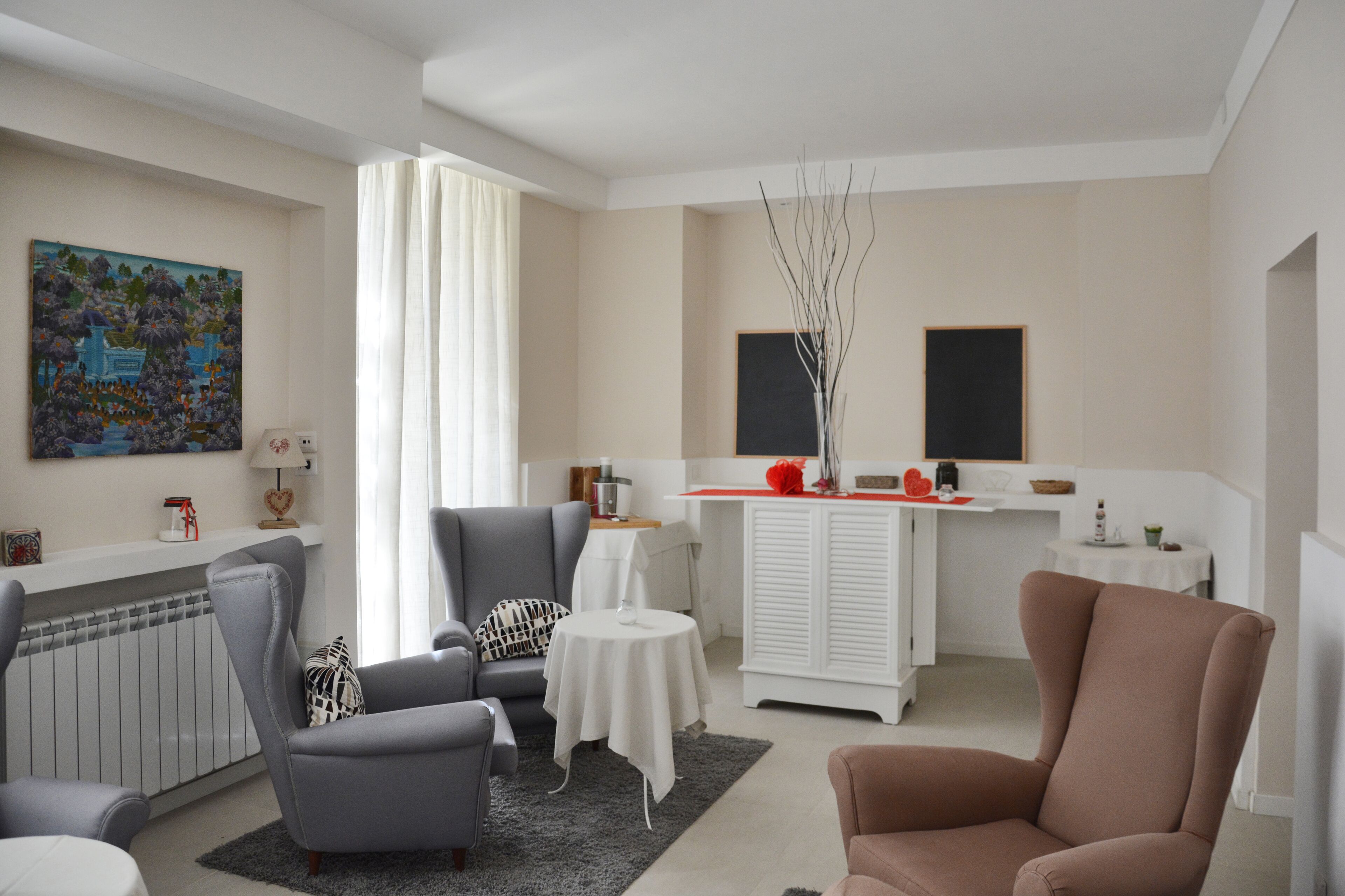 En moderne stue med en grå sofa, en brun lænestol, et lille rundt bord og et hvidt skab.
