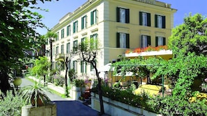 A hotel with a classic facade, multiple windows, and a balcony with flowers. - Hotel Touring Wellness & Beauty (Fiuggi)