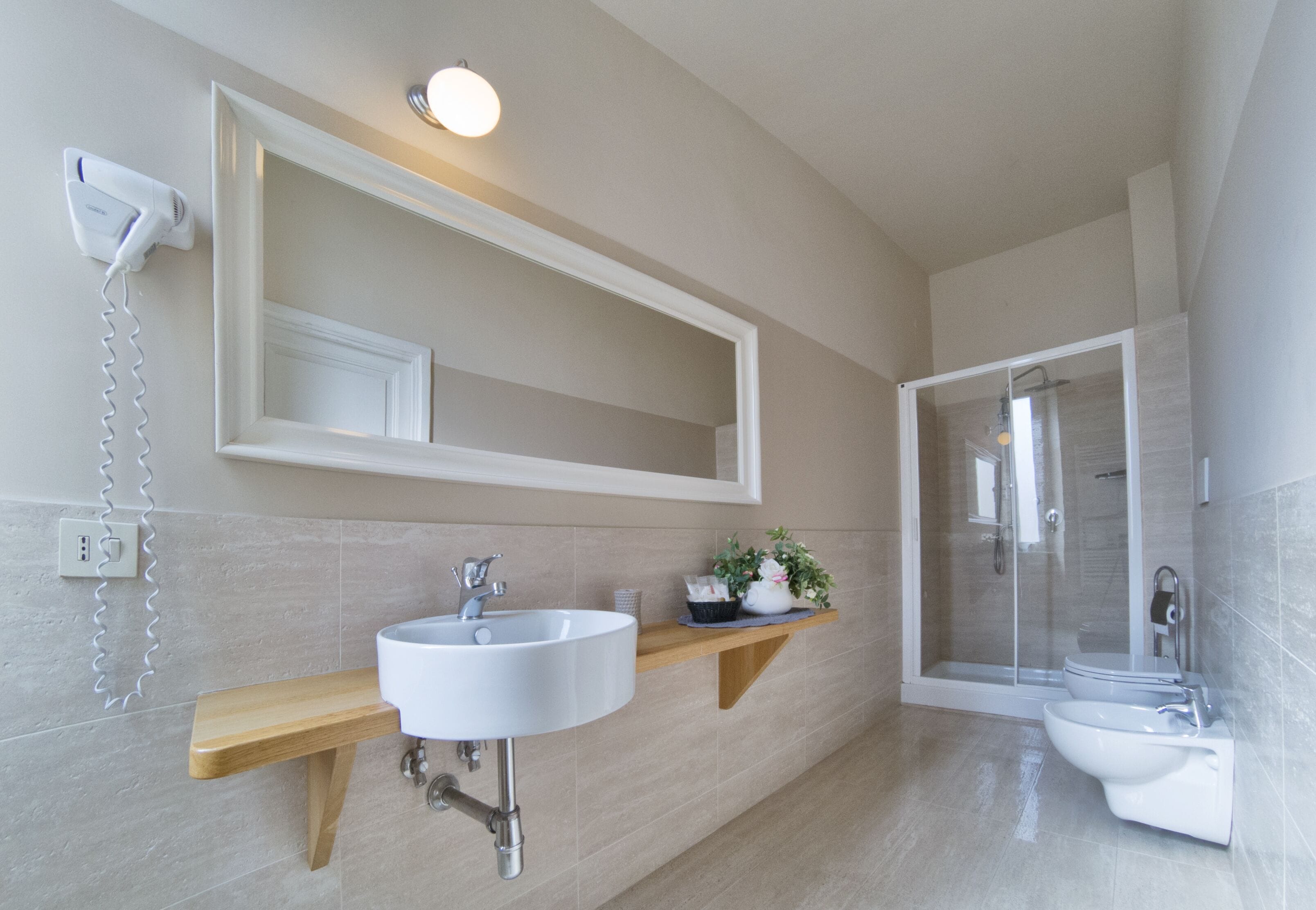 A modern bathroom with a large mirror, a sink, a toilet, and a shower.