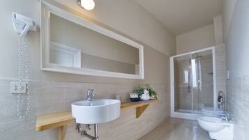 A modern bathroom with a large mirror, a sink, a toilet, and a shower.