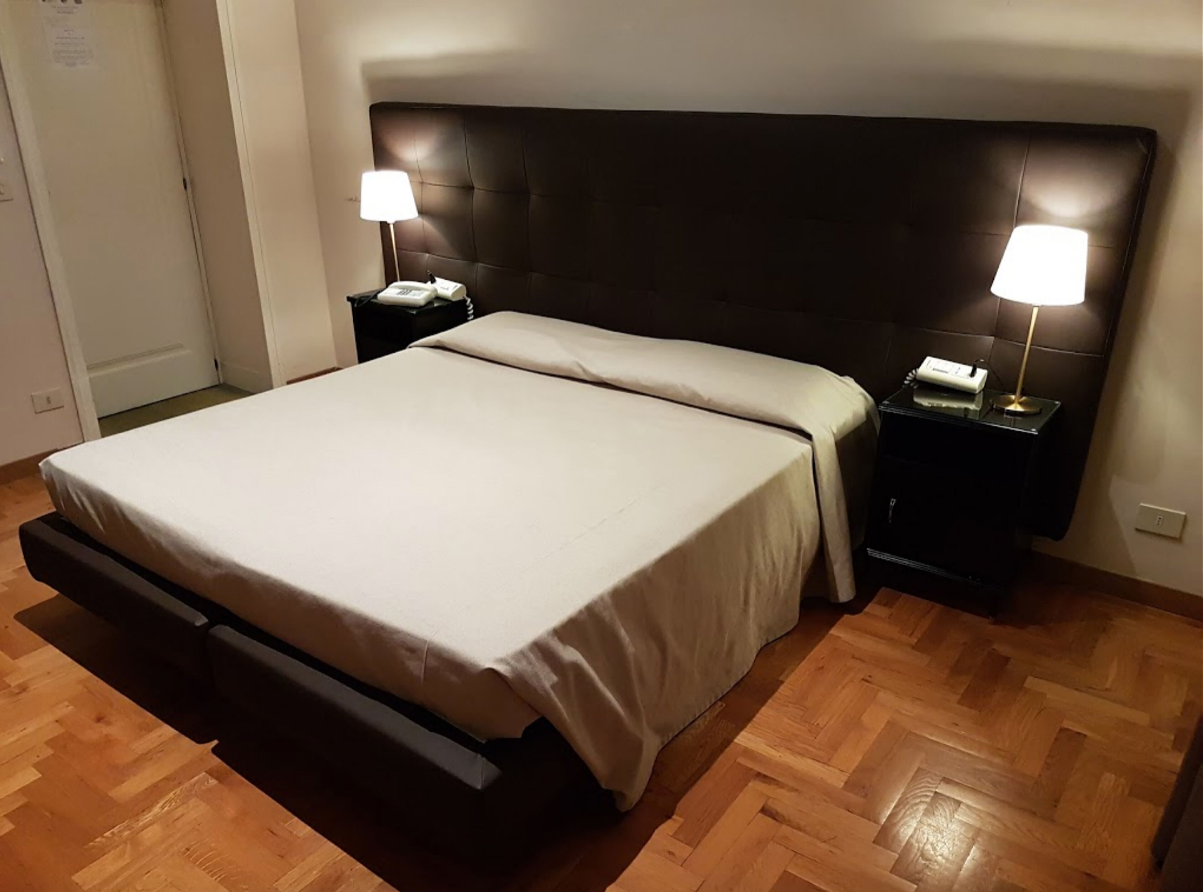 A hotel room with a bed, two bedside tables, and a nightstand.