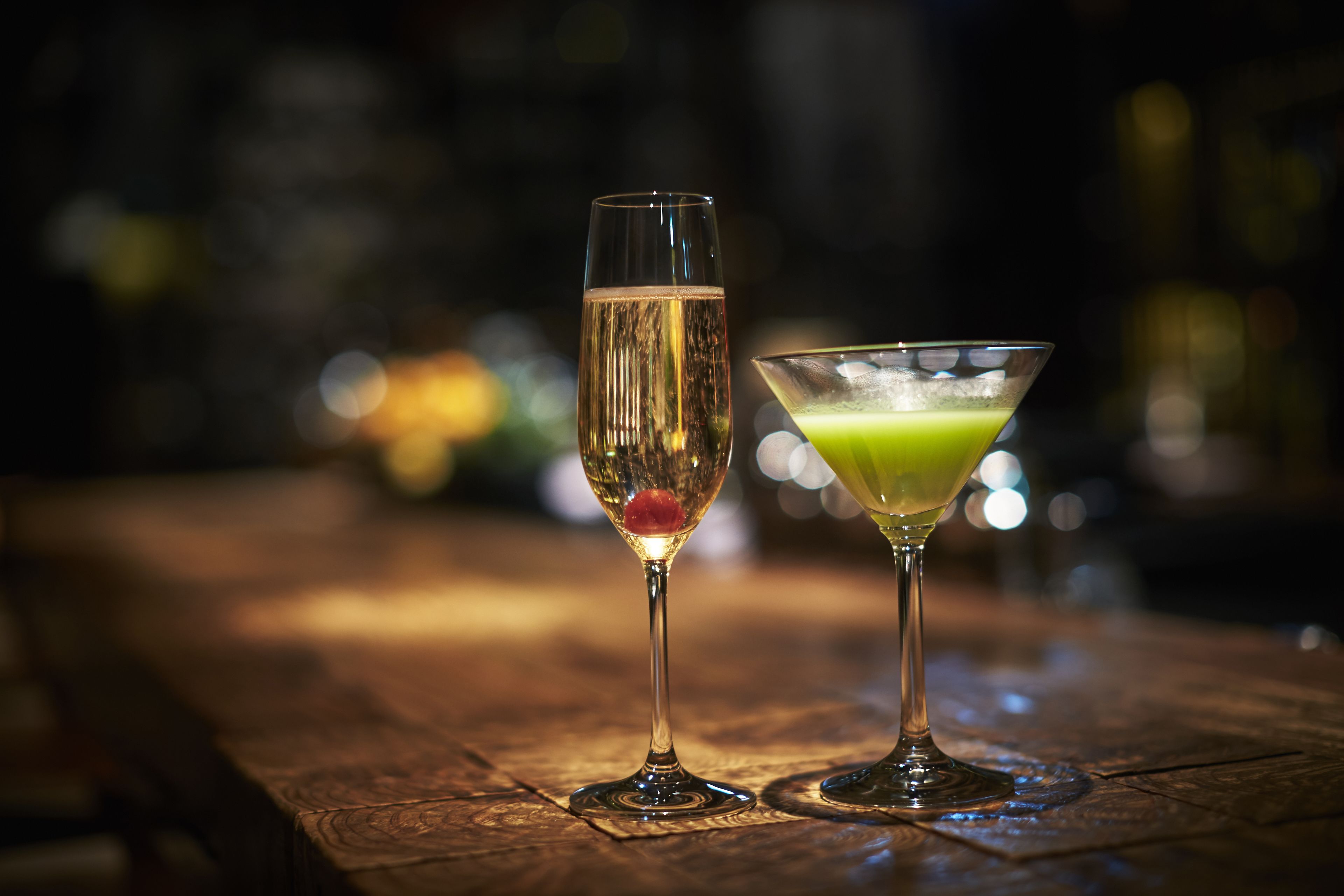 Two glasses of cocktails on a wooden table.