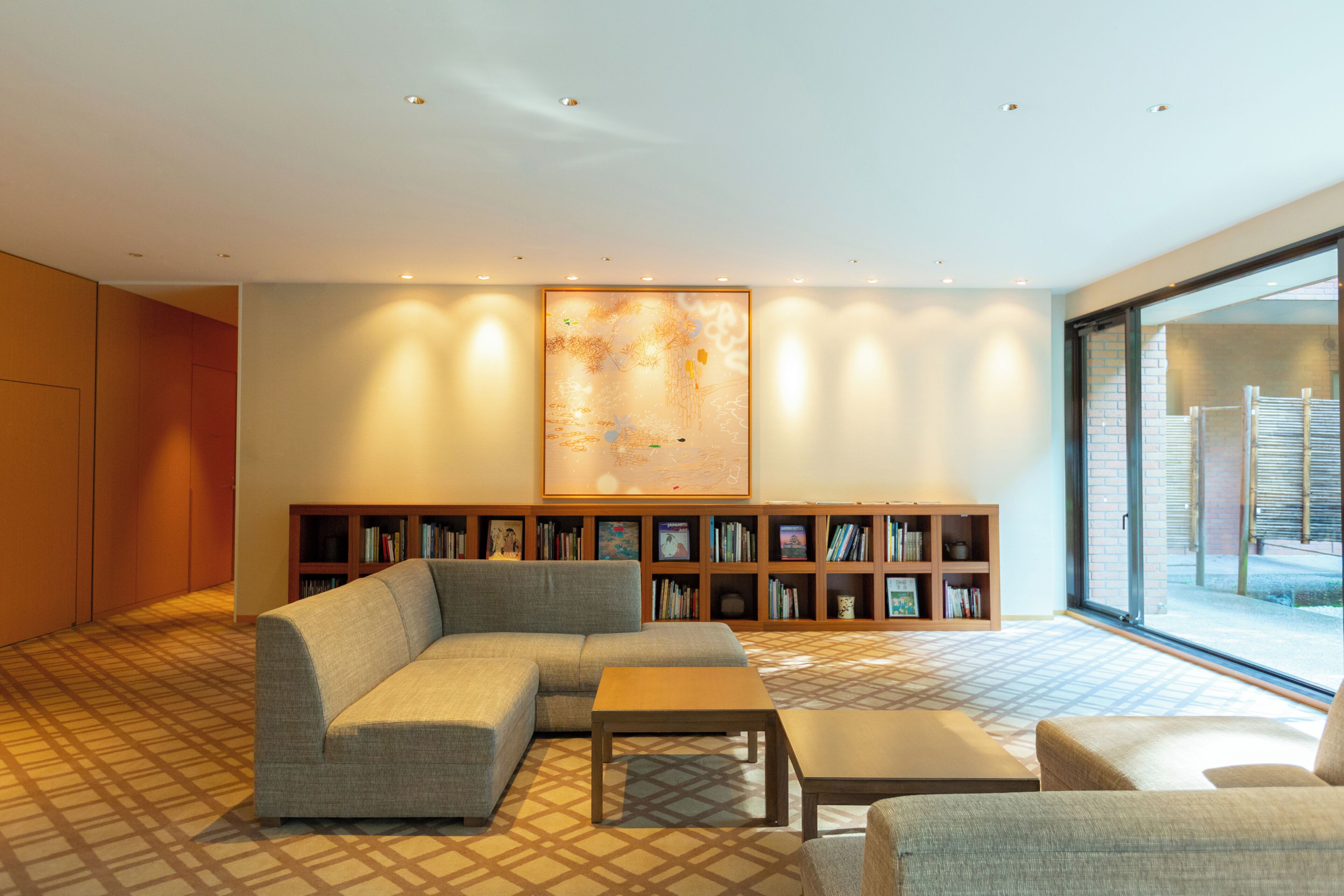 A modern living room with a sectional sofa, a small table, and a bookshelf filled with books.