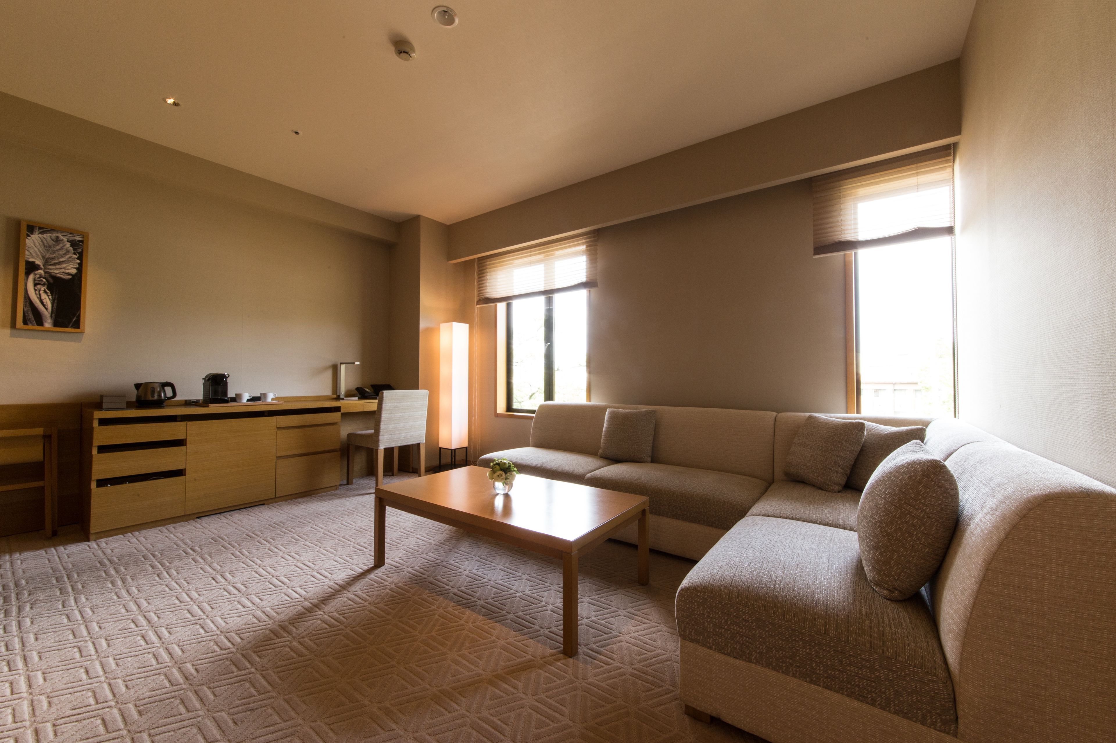 A modern living room with a sofa, a coffee table, and a desk with a lamp.