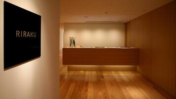A reception area with a wooden reception desk, a wall-mounted sign, and a wooden floor.