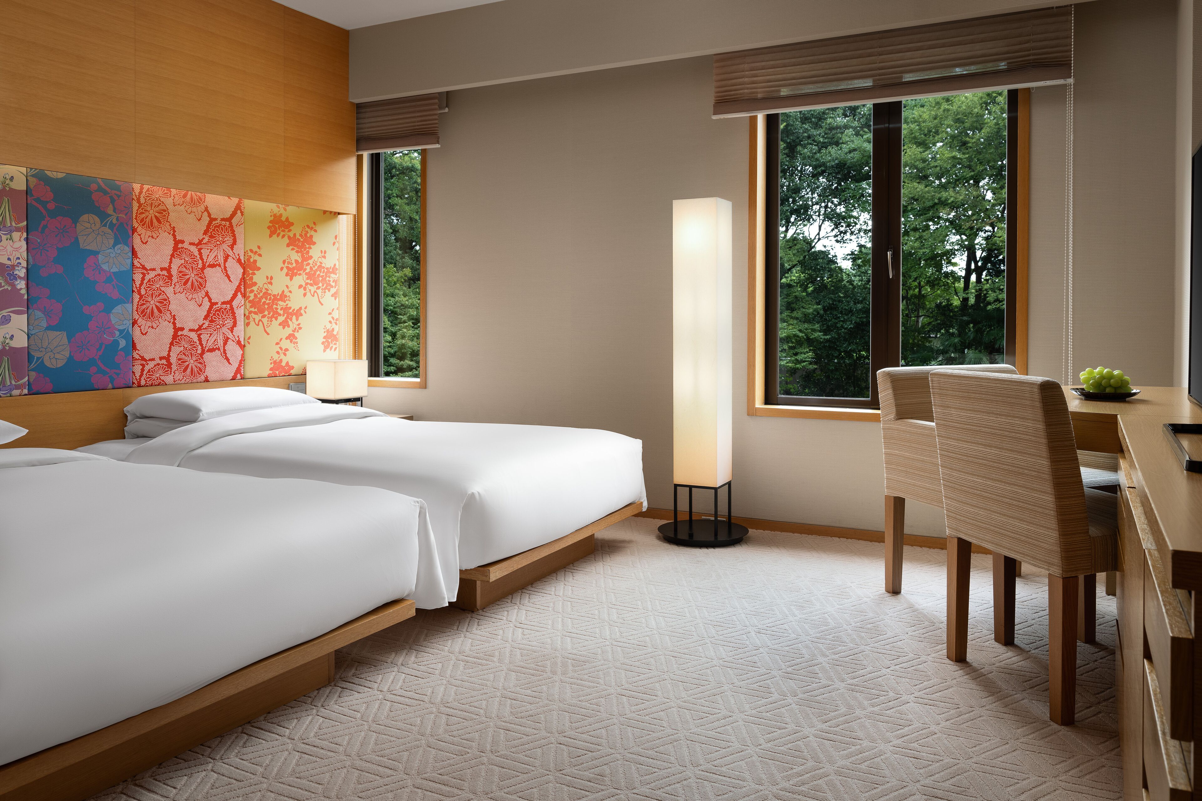 A hotel room with two beds, a desk, and a chair.