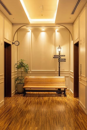 A hotel lobby with a wooden bench, a directional signpost, and a potted plant. - Akihabara Washington Hotel (Tokyo)