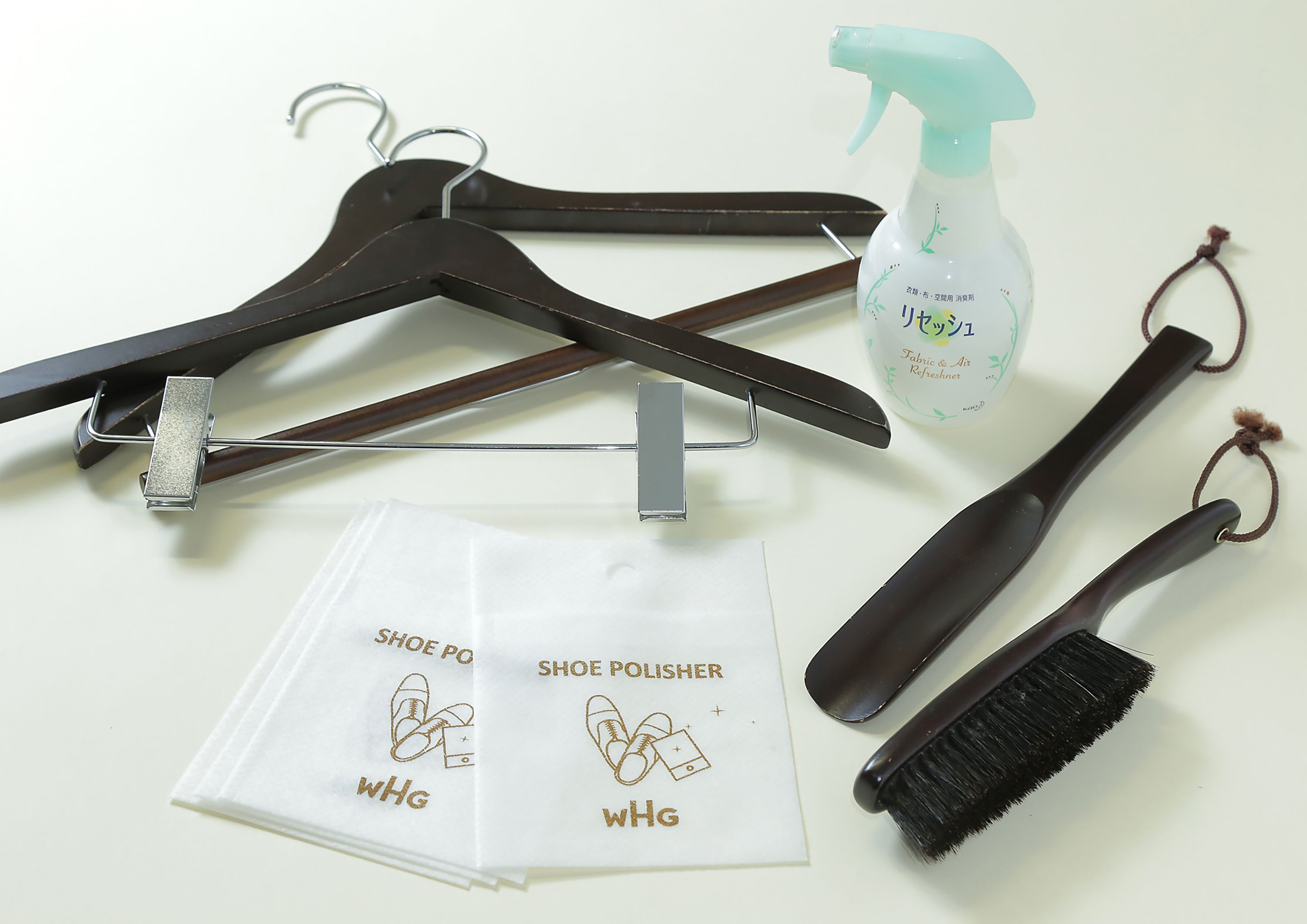 A shoe care kit with a spray bottle, brush, polish, and hangers.