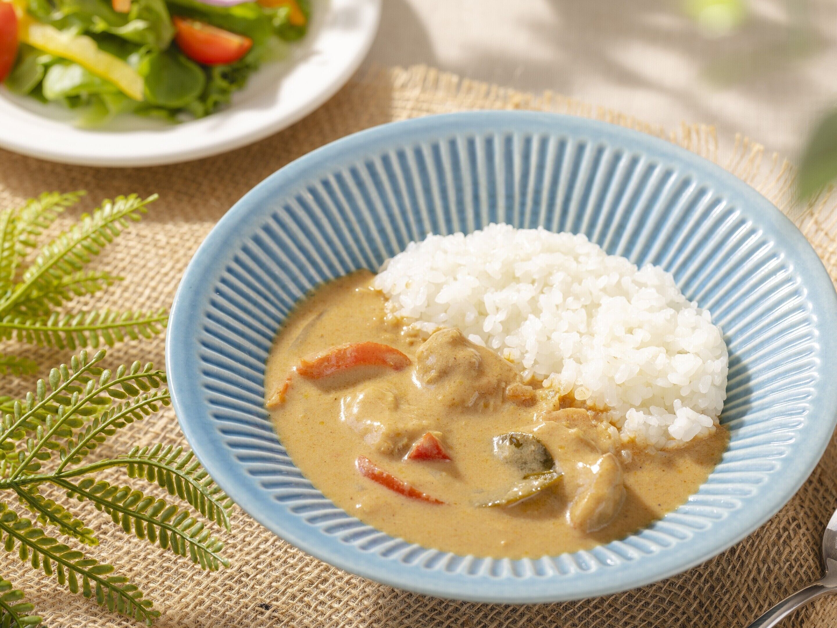 A bowl of creamy soup with vegetables and rice on a blue plate.