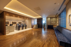 A hotel lobby with a reception desk, self-service kiosks, a seating area, and a wooden floor. - Akihabara Washington Hotel (Tokyo)