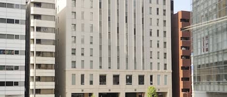 A modern hotel building with a prominent entrance and a sign indicating directions to nearby facilities.