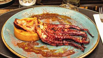 Un plato con pulpo y un pan sobre una mesa.