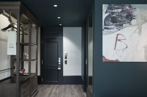 Un pasillo con un armario de madera, una puerta negra y una pared con una gran letra 'B'.