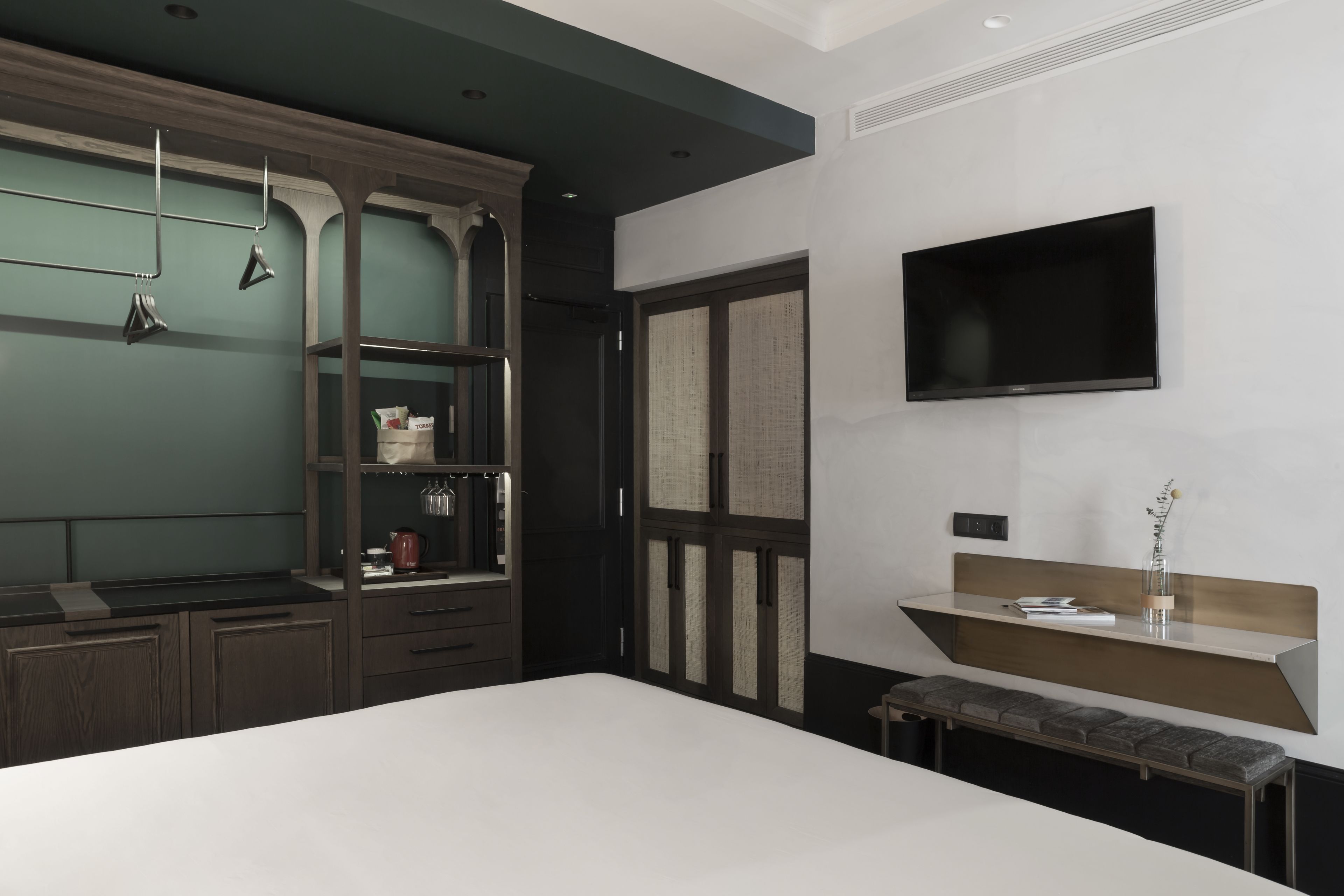Un dormitorio moderno con una cama grande, armario empotrado y televisor de pantalla plana montado en la pared.
