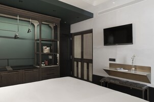 Een moderne slaapkamer met een groot bed, een inbouwkast en een flatscreen televisie aan de muur.