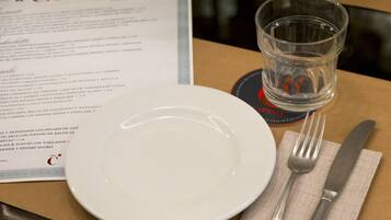 Una mesa con un menú, un vaso de agua, un plato y cubiertos.