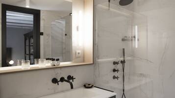 Un baño moderno con un lavamanos blanco, un espejo grande y una ducha con cerramiento de vidrio.