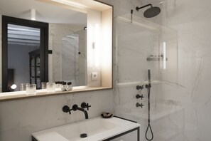 A modern bathroom with a white sink, a large mirror, and a glass-enclosed shower. - ICON Wipton (Madrid)