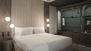 Una habitación de hotel moderna con una cama grande, lámparas de noche, un cabecero de madera, un armario y un pequeño cubo de basura.