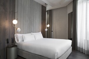Ein modernes Hotelzimmer mit einem großen Bett, einem Nachttisch, einer Lampe und einem Telefon.