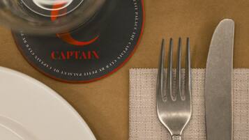 Una mesa dispuesta con un plato, una copa, un tenedor y un cuchillo sobre una servilleta.