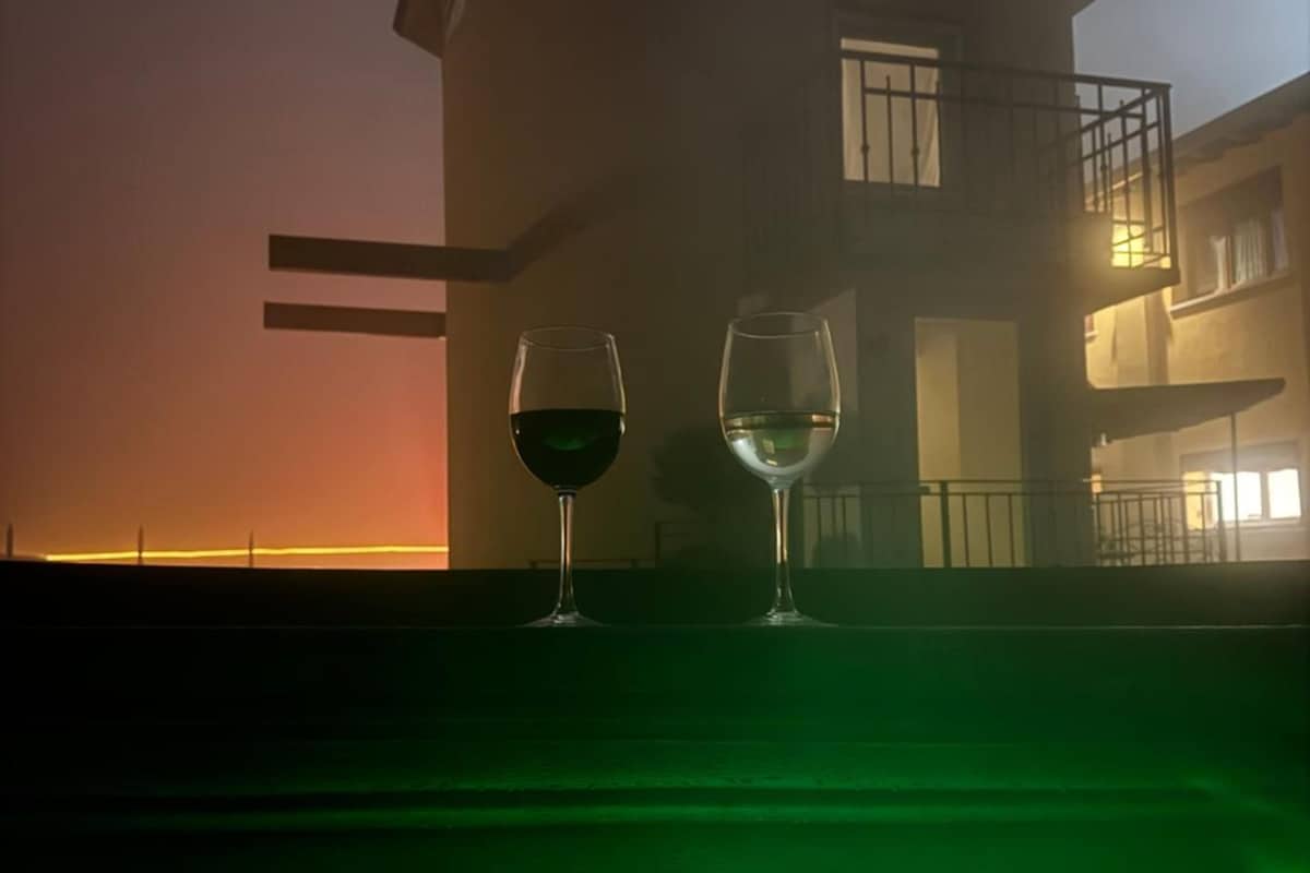 A building with a balcony and a table with two glasses of wine.