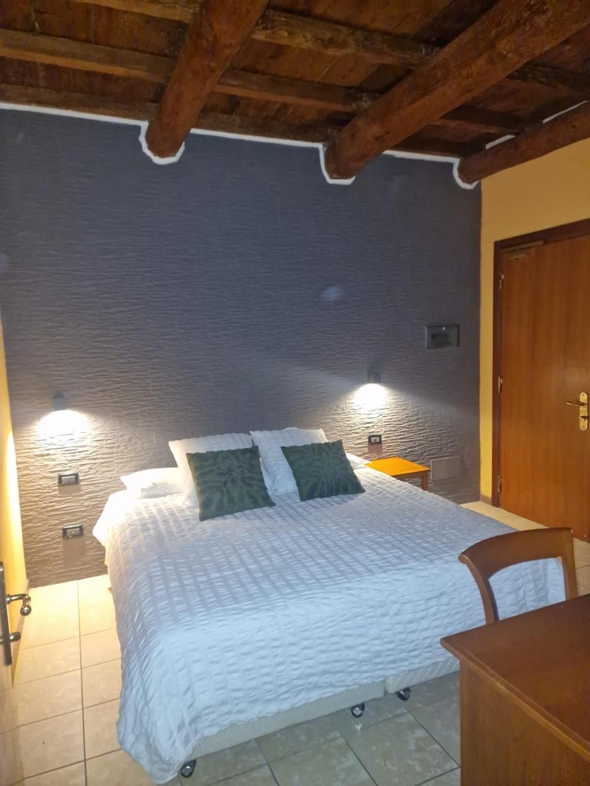 Ein Zimmer mit einem Bett, einem Holzstuhl und einer Tür.
