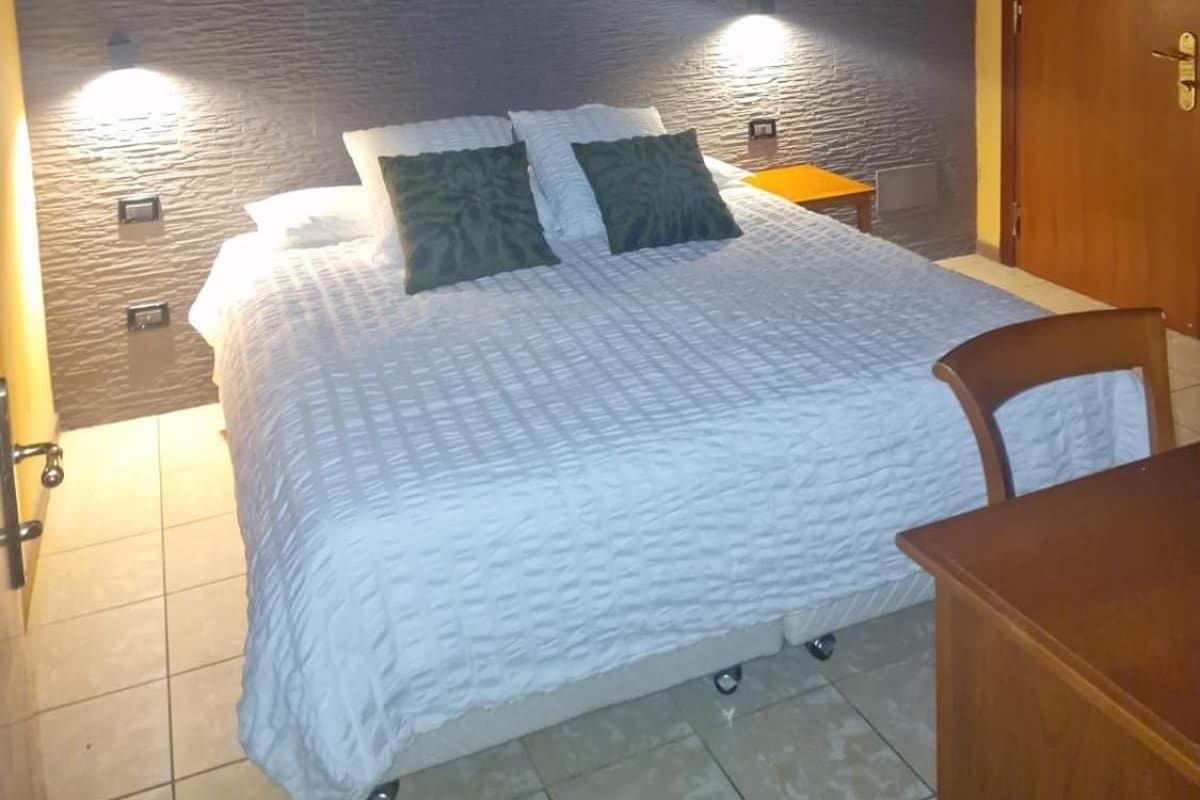 A room with a bed, a wooden chair, and a door.