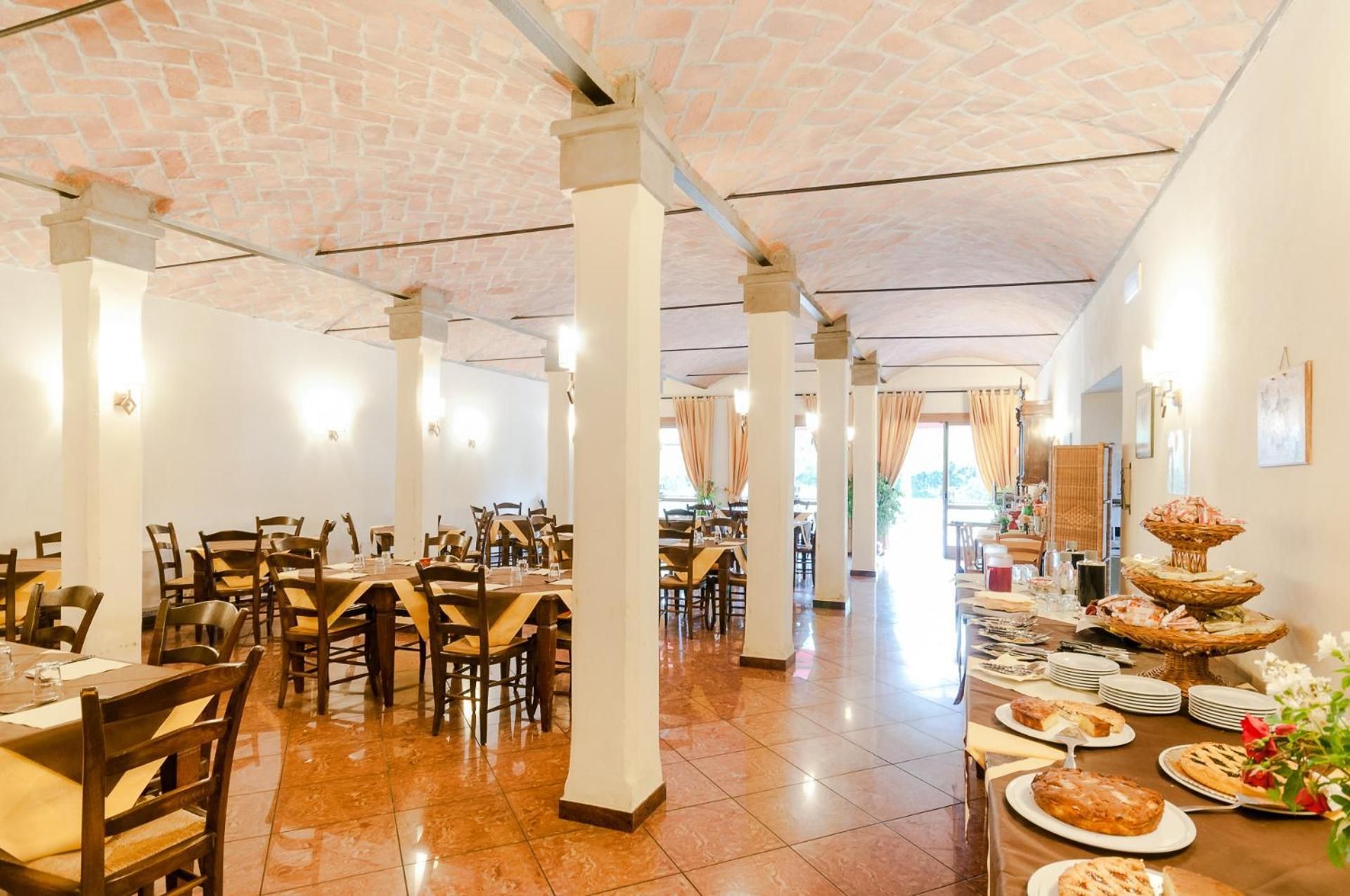 Un restaurant spacieux avec de hauts plafonds, de nombreuses tables et une variété de plats présentés sur les tables.
