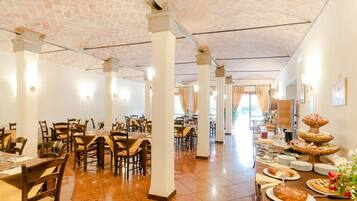 Un restaurant spacieux avec de hauts plafonds, de nombreuses tables et une variété de plats présentés sur les tables.