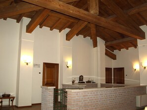 A room with exposed wooden beams, a brick counter, and wall-mounted light fixtures.