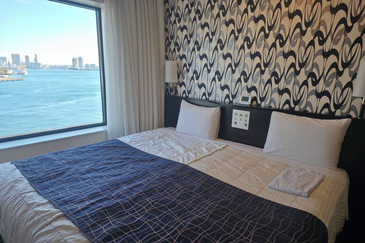 Une chambre d’hôtel avec un grand lit, une vue sur l’eau et un mur décoré de motifs.